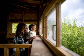 A woman and child looking out from a bird hide into the reedbed