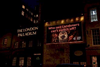 People walk past The London Palladium beneath a large London Wildlife Trust billboard showing a hedgehog with the message, “Who said Londoners can’t switch off?”